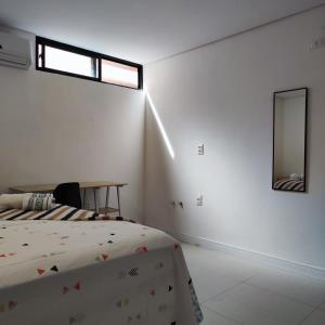 Habitación blanca con cama y espejo en Casa Sagrada 282, en Fortaleza