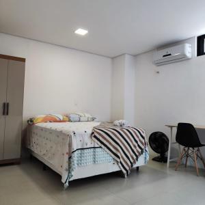 a white bedroom with a bed and a table at Casa Sagrada 282 in Fortaleza