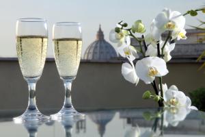 zwei Gläser Champagner neben einer Vase weißer Blumen in der Unterkunft Hotel Alessandrino in Rom