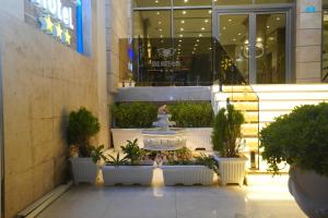 a building with a fountain and potted plants on the sidewalk at Soulmate Hotel Erbil in Erbil