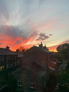 einen Sonnenuntergang über den Dächern von Gebäuden in einer Stadt in der Unterkunft Spacious, Sunny Double Bedroom in Home Stay Quirky Cottage, Near Holmfirth in Holmfirth