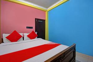 a bedroom with a bed with red and white pillows at Flagship Continental Stays Near Netaji Subhash Chandra Bose International Airport in Gauripur