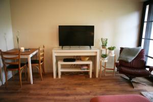 uma sala de estar com televisão e uma mesa com cadeiras em Blainroe Cottage 