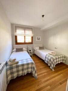 a bedroom with two beds and a window at Apartamento familiar en el centro de Benasque con terraza in Benasque