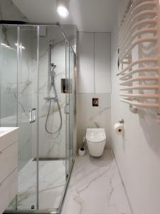 a bathroom with a glass shower and a toilet at Apartament zielony Mokotów in Warsaw