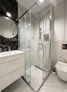 a bathroom with a glass shower and a sink at Apartament zielony Mokotów in Warsaw