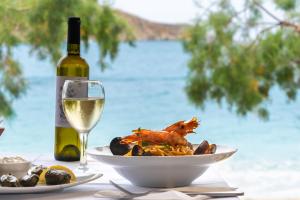 a table with a glass of wine and a plate of food at Alexandros by the Beach - Serifos in Livadakia