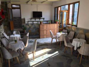 a restaurant with white tables and chairs and a tv at Hostel Mateo in Gjirokastër