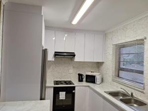 a kitchen with white cabinets and a sink and a microwave at Asher's Place in East London