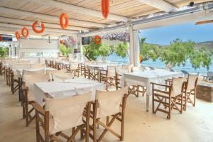 a restaurant with white tables and chairs and the ocean at Alexandros by the Beach - Serifos in Livadakia