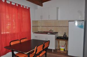 cocina con mesa, sillas y nevera en Aire de Campo en Gualeguaychú