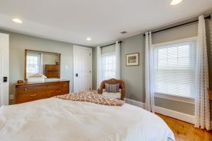 a bedroom with a bed and a dresser and windows at Greenport Home with Harbor View Near Ferry and Beaches in Greenport