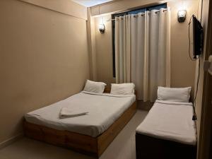 two beds in a small room with a mirror at Samanbha Guest House in Shillong