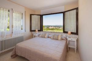 ein Schlafzimmer mit einem großen Bett und zwei Fenstern in der Unterkunft Hotel Rural y Apartamentos Villa Engracia in L’Espluga de Francolí