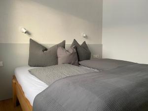 1 dormitorio con 1 cama con almohadas grises en Apart Mark, Stanz bei Landeck - Moderne Wohnung in sonniger Lage, en Stanz bei Landeck