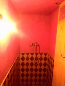 uma casa de banho com um chuveiro num quarto vermelho em دارالضيافة git atlas em Megdaz