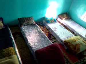 um quarto com três camas num quarto em دارالضيافة git atlas em Megdaz