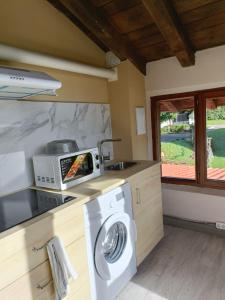 a kitchen with a washing machine and a microwave at Eguzkitza in Iturriotz