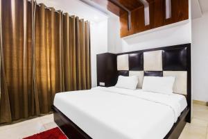 1 dormitorio con cama blanca y cabecero negro en OYO Hotel Br Villa, en Nārnaul
