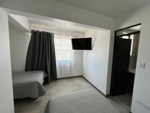 Habitación pequeña con cama y ventana en Hotel Santa María, en Iquique