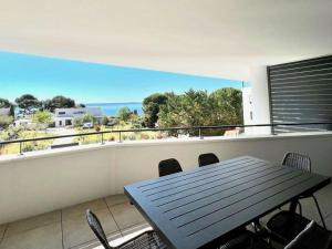 a balcony with a table and chairs and a view of the ocean at Appartement Mèze, 3 pièces, 4 personnes - FR-1-604-37 in Mèze