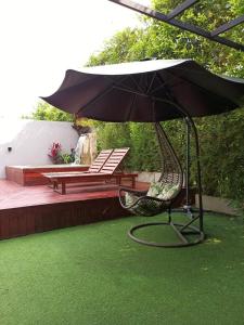 a patio with an umbrella and a chair on the grass at Hotel Suites Lounge La Viga in Cali
