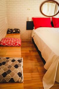 a bedroom with a bed with red pillows and a mirror at Casa da Cacaia e do Henrique in Rio de Janeiro