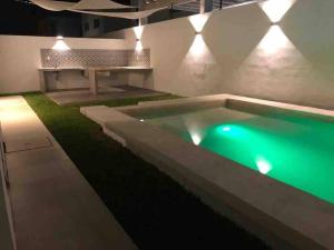 una piscina con illuminazione verde in una casa di Velamar, casa con alberca y asador a Miramar