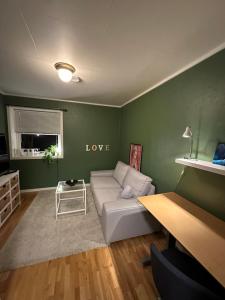 a living room with a white couch in a green wall at Sentral pen leilighet 