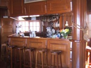 a kitchen with wooden cabinets and bar stools at Vila Ventura in Caniço