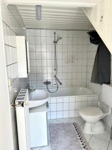 a bathroom with a tub and a toilet and a sink at Bequemes und helles Einfamilienhaus mit Garten in Weil am Rhein