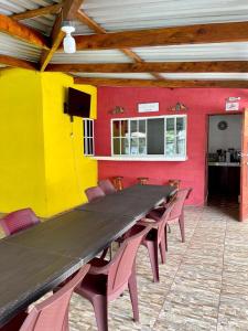 a long wooden table in a room with red and yellow walls at RANCHO BOLMAR. Playa Metalio. Sonsonate. in Acajutla