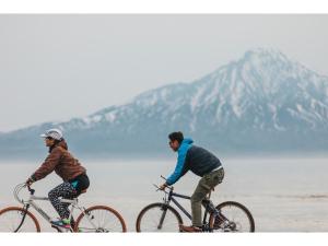 dois homens a andar de bicicleta numa praia perto da água em THE STAY WAKKANAI - Vacation STAY 40679v em Wakkanai
