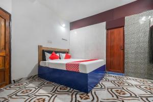 a bedroom with a bed with red pillows on it at OYO Ares Residency in Bhubaneshwar