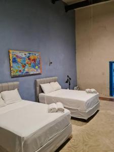 Habitación con 2 camas y una pintura en la pared. en Casa Hacienda Estrada, en Campeche