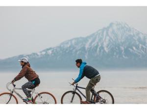 two men riding bikes on a beach near the water at THE STAY WAKKANAI - Vacation STAY 40658v in Wakkanai