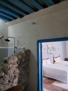 1 dormitorio con cama blanca y pared de piedra en Casa Hacienda Estrada, en Campeche