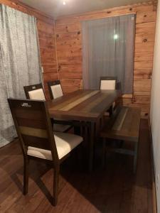 - une table à manger avec des chaises et un mur en bois dans l'établissement Barefoot Cabin, 