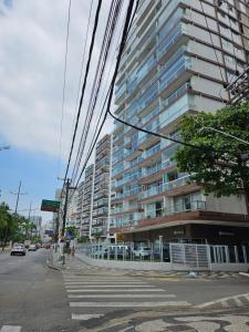 ein hohes Gebäude in einer Stadtstraße mit einem Fußweg in der Unterkunft Apartamentos na Praia do Gonzaga in Santos