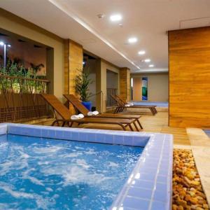 une chambre d'hôtel avec piscine et chaises dans l'établissement Olímpia Park Resort ao lado do Thermas dos Laranjais - Apartamento Luxo, à Olímpia