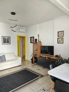 ein Wohnzimmer mit einem weißen Sofa und einem TV in der Unterkunft Apartamentos na Praia do Gonzaga in Santos