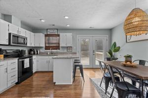 a kitchen with white cabinets and a table with chairs at Beautifully updated home! Near downtown & NC State in Raleigh