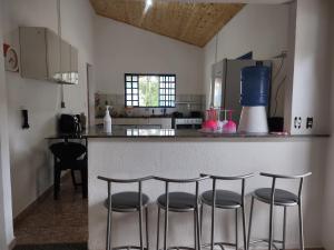 a kitchen with a counter with four bar stools at Sítio Cantinho da Cachoeira in Guapé