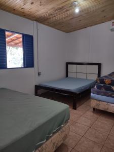 a room with two beds and a window at Sítio Cantinho da Cachoeira in Guapé