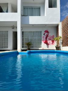 uma piscina em frente a um edifício com uma pintura de flamingo em Hostel Killamoon Centro em Paracas