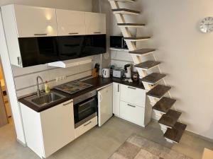 una cocina con armarios blancos, un lavabo y una escalera en Apartment Adi, en Slavonski Brod