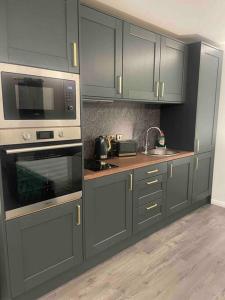 una cocina con armarios grises y electrodomésticos de acero inoxidable en Woodland lodge green room en Dungiven