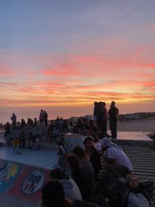 una multitud de personas viendo la puesta de sol en un parque de patinaje en sunny wave taghazout SURF & YOGA, en Taghazout