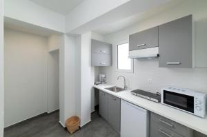 a white kitchen with a sink and a microwave at Serenita apartments 2 in Agios Nikolaos