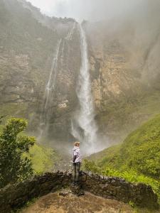 a woman standing on a wall looking at a waterfall at GoctaLab in Cocachimba